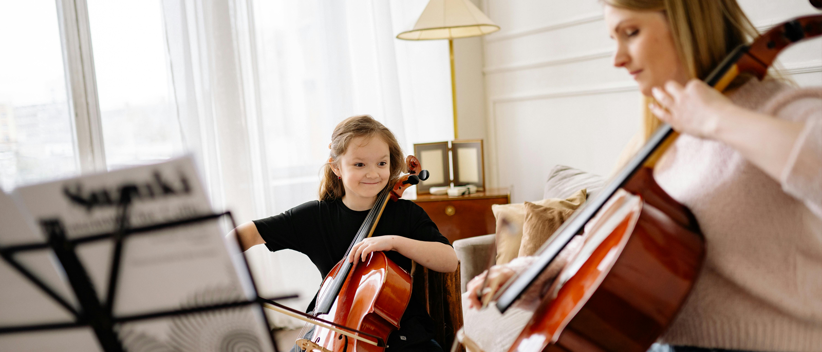 A young music student studies cello with her teacher.